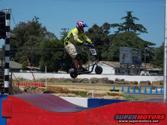 Person on scooter airborne over ramp, number 884 visible