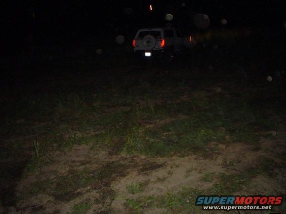 1993 Ford Bronco parked at night, rear view showing spare tire on tailgate and illuminated taillights