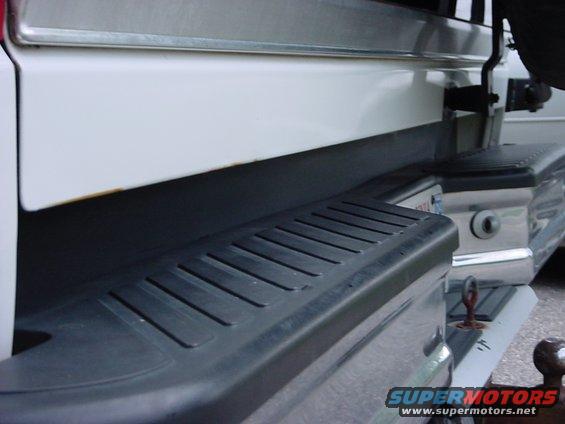 White SUV rear bumper with step and tow hitch. Watermark reads SUPERMOTORS.NET