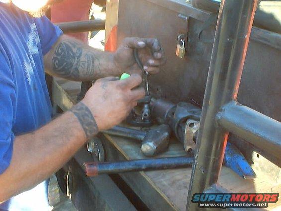 Man with tattoos working on driveshaft and U-joint components