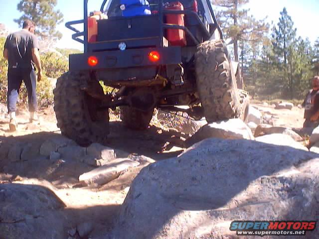 Rear view of off-road vehicle with large tires navigating rocky terrain