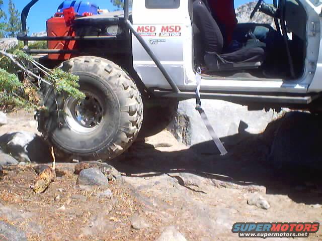 Off-road truck with large tires, roll cage, and jerry cans on the side