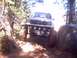 1976 Ford F-100 - This modified pickup truck navigates a rocky off-road trail through a wooded area.