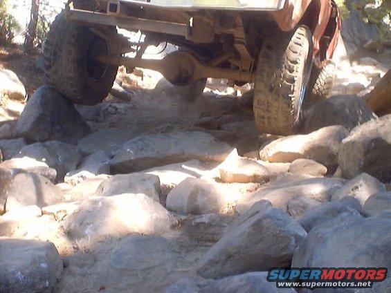Off-road vehicle's undercarriage and tires navigating a rocky trail