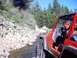 1976 Ford F-100 - Red Jeep Wrangler navigates a shallow stream on a wooded trail.