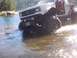 1976 Ford F-100 - A modified pickup truck navigates through a body of water, its large tires splashing.