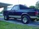 1988 Ford Bronco - This 1988 Ford Bronco is viewed from the rear three-quarter angle, showing its distinctive two-tone paint and soft top.