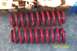 1996 Ford Bronco - Pair of red coil springs shown on a concrete surface with stacked wood behind them.