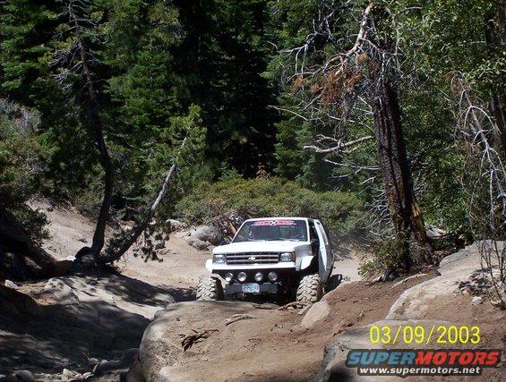 White off-road truck with large tires navigating a rocky trail