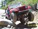1976 Ford F-100 - A red Jeep Wrangler tackles a challenging rocky off-road course, demonstrating its suspension and tire grip.