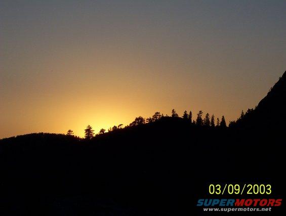 Sunset over silhouetted mountains with date 03/09/2003 and Supermotors.net text