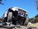 1976 Ford F-100 - A heavily modified white truck navigates a rocky trail under a clear blue sky.