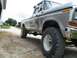 1979 Ford F-150 - A lifted 1979 Ford F-150 sits on a gravel driveway with other vehicles in the background.