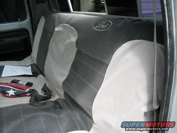 Back seat of a Ford truck with a "Ford" logo on the headrest. A seatbelt is visible