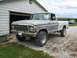 1979 Ford F-150 - A silver 1979 Ford F-150 pickup truck is parked on a gravel driveway next to a white garage, with another vehicle visible in the background.