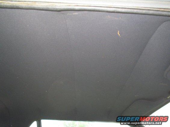 Dark gray car headliner with a small yellow stain visible