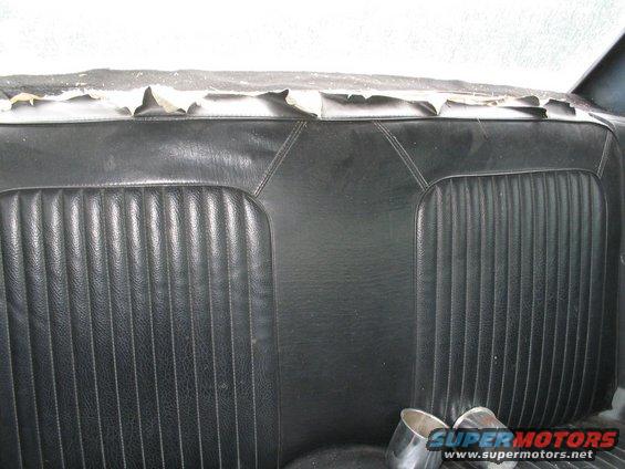 Back seat of a car with worn upholstery and chrome exhaust tips visible