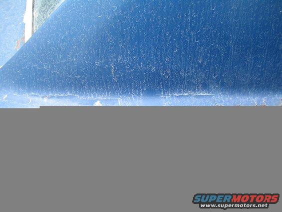 Close-up of a blue car door with visible scratches and dust