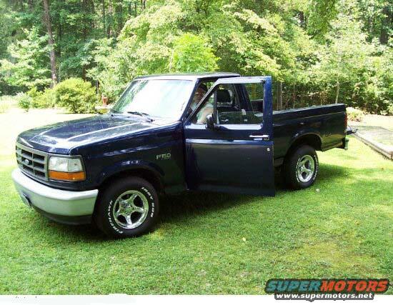 Dark blue 1994 Ford F-150 pickup truck with driver's door open, parked on grass