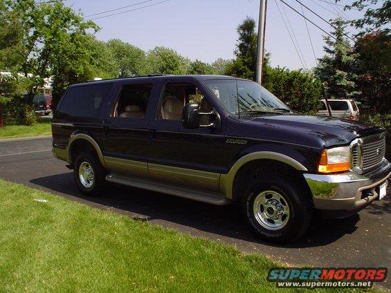 Dark blue 2000 Ford Excursion parked on asphalt driveway, tan lower body trim, chrome wheels, front passenger side visible