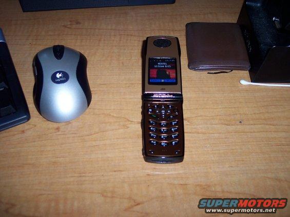 Brown flip phone and Logitech mouse on a wooden desk