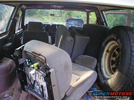 Interior of a 1986 Ford Bronco with seats removed and a spare tire visible