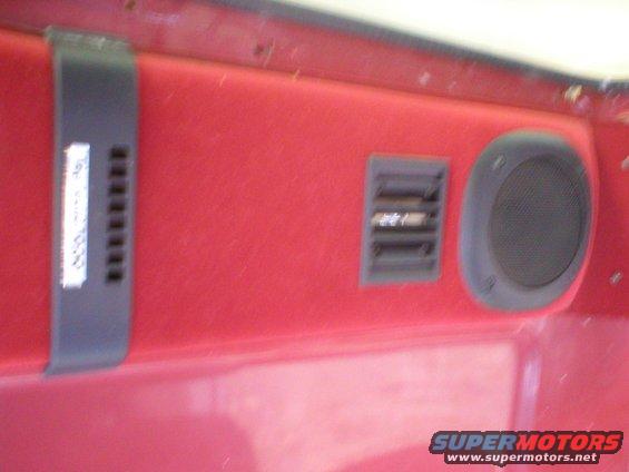 Red interior panel with a black speaker, air vent, and a label with text