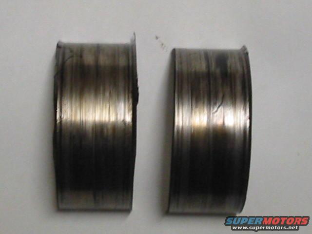 two worn engine bearings with scoring and discoloration