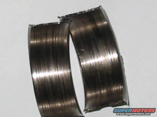 Worn engine bearing halves with visible scoring and damage