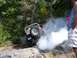 1990 Ford Bronco - A Jeep Wrangler navigates a challenging rocky course, kicking up a cloud of smoke.