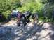 1990 Ford Bronco - Several off-road vehicles navigate a steep, rocky incline on a wooded trail.