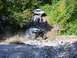 1990 Ford Bronco - An off-road vehicle navigates a challenging rocky terrain with spectators watching.