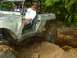 1990 Ford Bronco - An off-road vehicle navigates a dirt trail with two occupants.