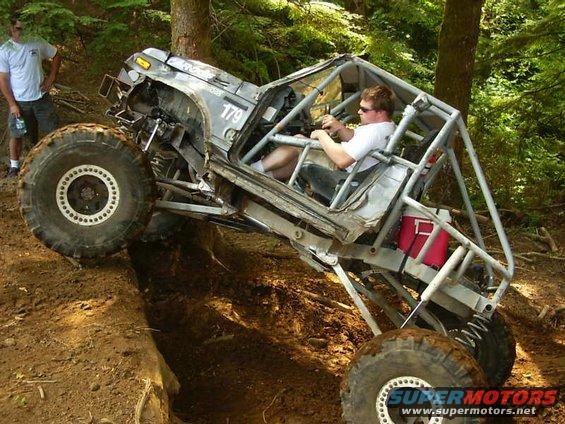 Buggy with roll cage going over an obstacle on a dirt trail