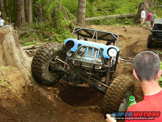 Blue off-road buggy with large tires climbing a dirt hill