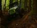 1990 Ford Bronco - An off-road vehicle navigates a steep, wooded trail.