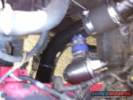 Engine bay with black hose, blue blow-off valve, and Supermotors.net logo