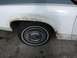 1988 Ford Crown Victoria - Close-up of a white sedan's front fender and wheel, showing signs of rust and wear.