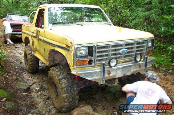 Yellow Ford Bronco with off-road tires on a rocky trail, front view