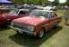 1967 Ford LTD - A red 1964 Ford Falcon coupe is displayed at an outdoor car show with other vehicles and people.