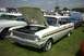 1967 Ford LTD - A white station wagon with its hood open is parked on a grassy field next to other vehicles.