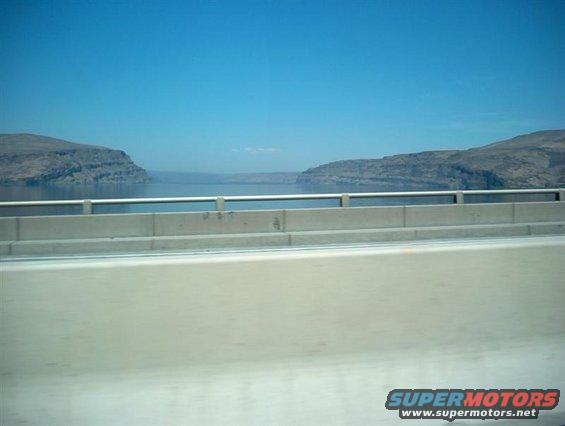 Water and hills seen from a bridge, with Supermotors.net logo