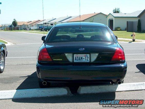 Dark 2001 Ford Crown Victoria parked rear-end to curb, Washington license plate ADAM-12