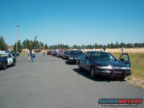 Black 2001 Ford Crown Victoria with open driver door, parked in a line of cars