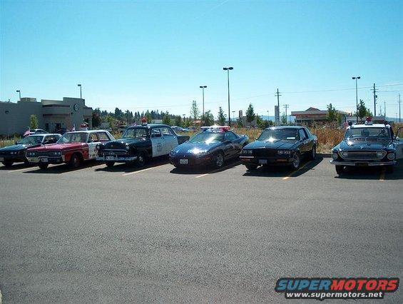 Several police cars parked in a lot under a clear sky