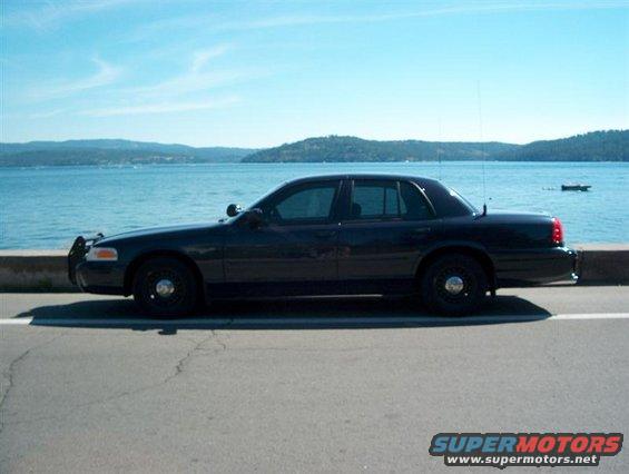 Dark 2001 Ford Crown Victoria parked by a body of water, side view