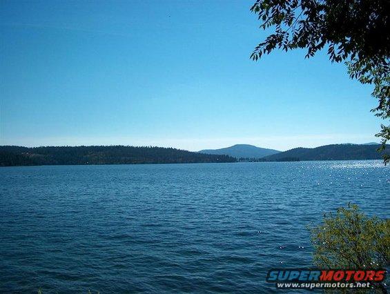 Lake with trees and mountains under a clear blue sky