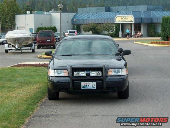 Front view of a black 2001 Ford Crown Victoria police car with push bar and license plate ADAM-12
