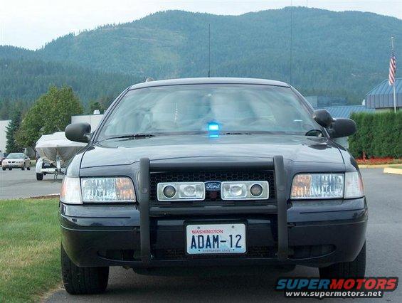 Black Ford Crown Victoria police car, front view, with push bar and blue lights