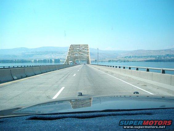Dashboard view driving over a bridge with a large metal truss structure